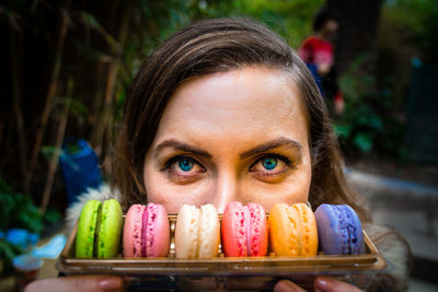 Close-up portrait of mid adult woman with colorful macaroons