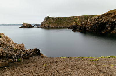 Rocks on shore by sea against sky