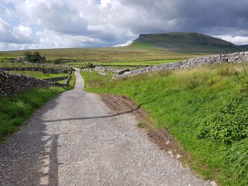 Road amidst field against sky