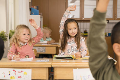 Girls in classroom raising hands