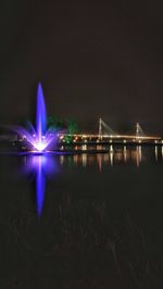 Illuminated bridge over river at night