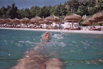 People swimming in pool by sea