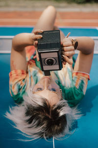 A young woman taking pictures with an analog camera in a colorful dress