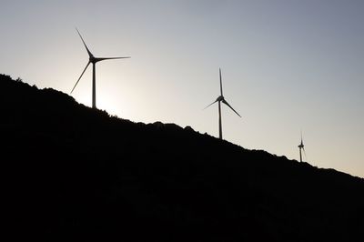 Low angle view of silhouette wind turbine against clear sky