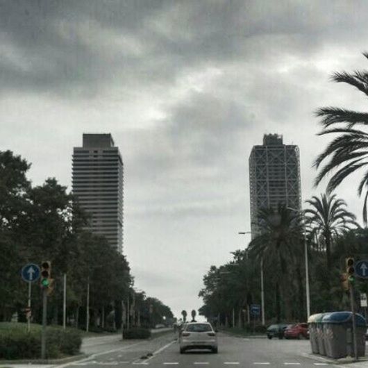 building exterior, architecture, built structure, car, transportation, land vehicle, city, sky, road, street, cloud - sky, mode of transport, tree, skyscraper, modern, tall - high, office building, cloudy, road marking, tower