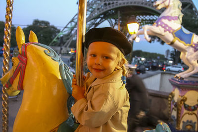 Portrait of cute boy with carousel in amusement park