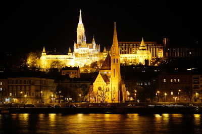 Illuminated cathedral in front of river at night