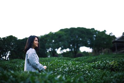 Woman smiling on field against clear sky