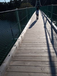 Rear view of man walking on footbridge