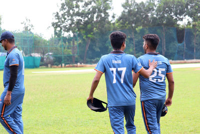 Rear view of friends standing on soccer field