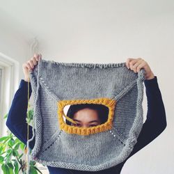 Portrait of young woman looking through knitted cloth