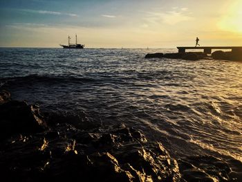 Silhouette person running on pier over sea against sky during sunset