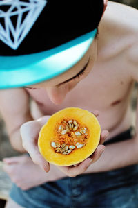 High angle view of shirtless boy holding pumpkin slice