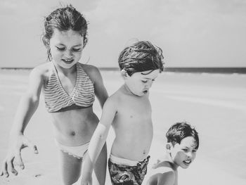 Siblings playing on shore at beach during summer