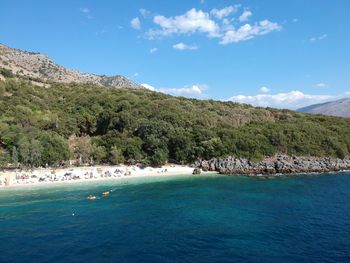 Scenic view of sea and mountains against blue sky