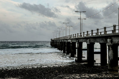 Bridge over calm sea against sky