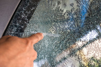 Close-up of person hand on wet window