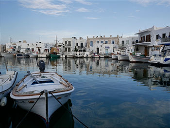 Sailboats moored on canal by buildings in city against sky