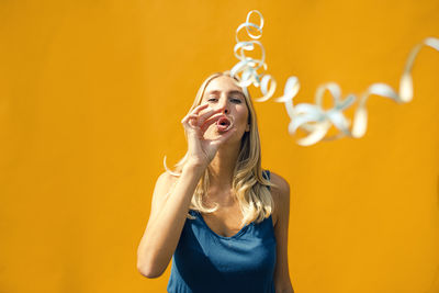 Portrait of a smiling young woman against yellow background