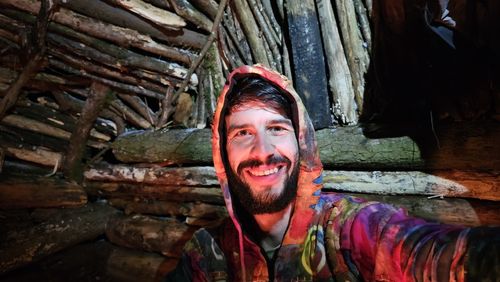 Portrait of young woman standing against tree trunk