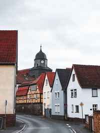 Road by buildings against sky