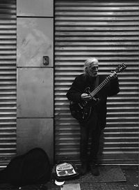 Man playing guitar against brick wall