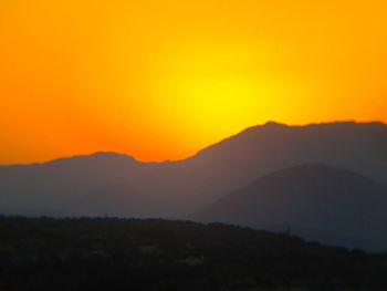 Scenic view of silhouette mountains against orange sky