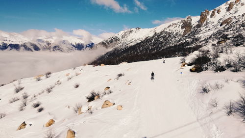 People skiing on snow covered mountain against sky