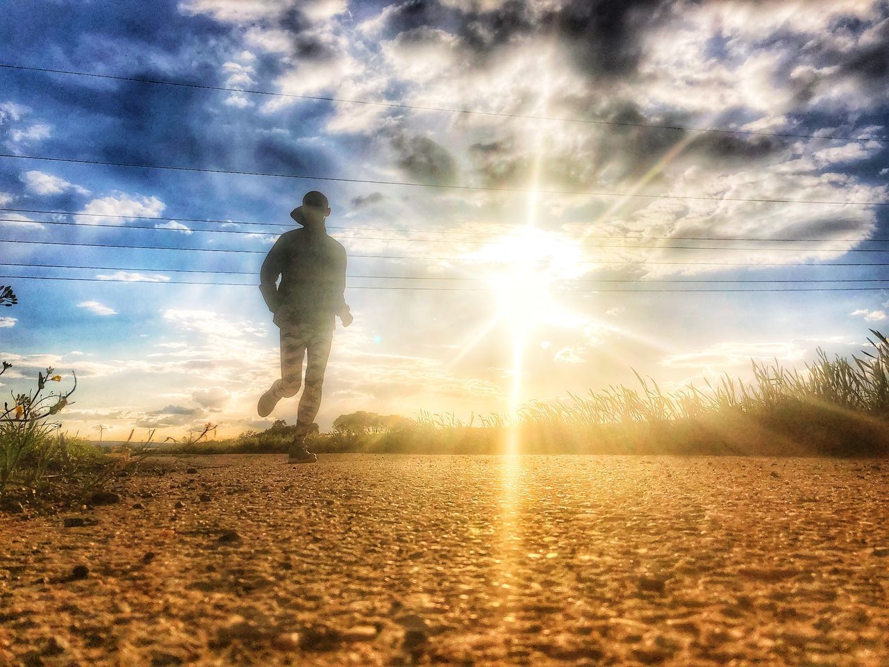 FULL LENGTH OF MAN STANDING ON FIELD AGAINST BRIGHT SUN