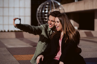 Boyfriend taking selfie with girlfriend over mobile phone outdoors