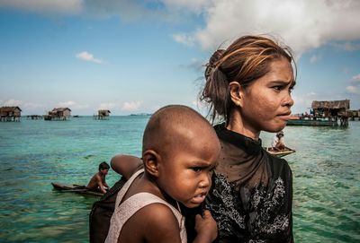 Father and son at beach against sky