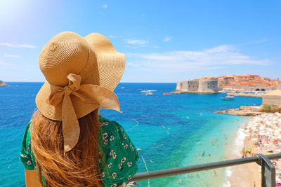 Rear view of woman with umbrella in sea against sky