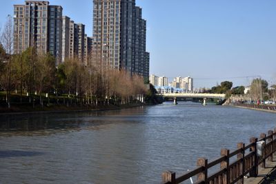 Buildings by river against sky in city