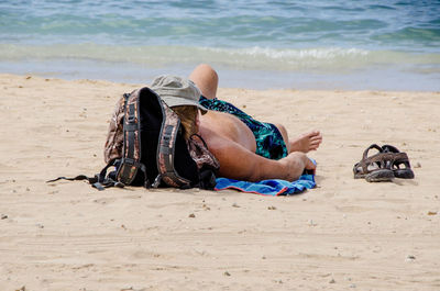 Low section of man sitting on beach