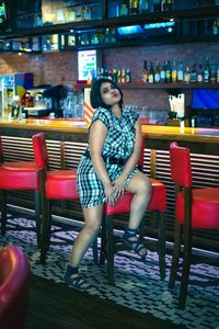 Full length portrait of woman sitting on chair