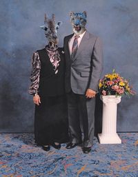 Couple wearing animal masks while standing against wall