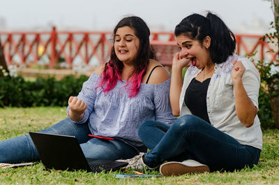 Cheerful friends using technology at park