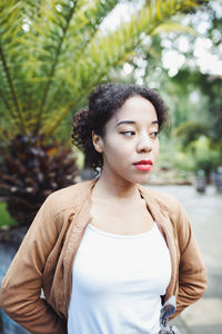Young woman standing against trees