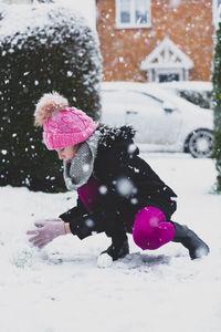 Girl playing in snow against building during winter