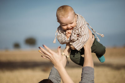 Father and mother playing with son against sky