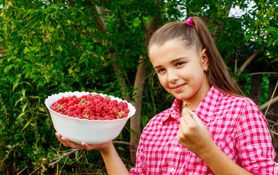 Girl eating berries while standing against plants