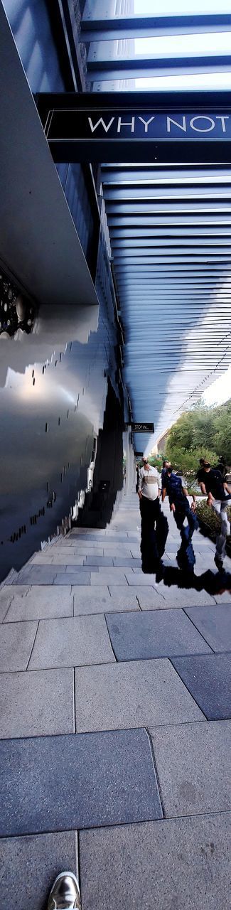 PEOPLE WALKING ON FOOTPATH BY STREET IN CITY