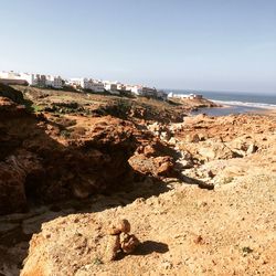 Rock formations by sea against clear sky