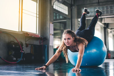 Full length of woman exercising on fitness ball in gym