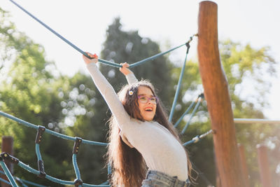 Caucasian  girl with a daisy in long brown flowing hair and a happy smile hangs on a rope swing