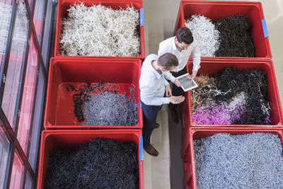 Two businessmen with tablet in factory standing at containers with shred