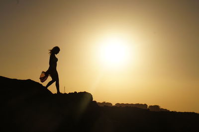 Silhouette man with arms raised against sky during sunset