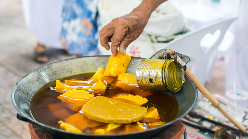 Cropped image of man making wax in pan during candle festival