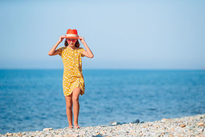 Full length of woman standing on beach against sky