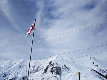 Low angle view of flag on snowcapped mountains against sky